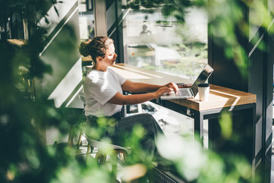 Young woman using mobile phone while sitting on table