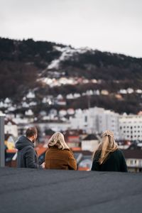 Rear view of people sitting against cityscape