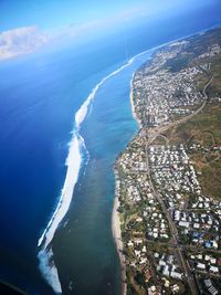 Aerial view of city by sea against sky