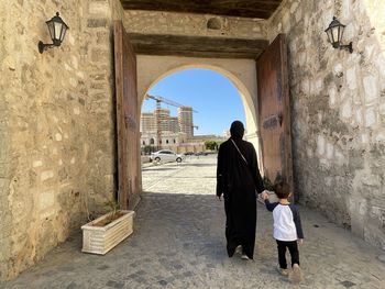 Rear view of woman standing against historic building