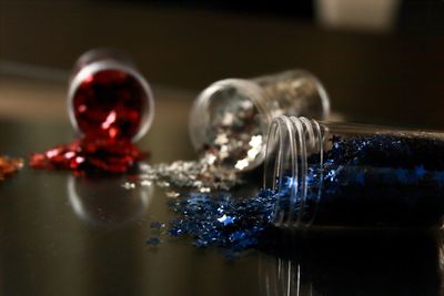 Close-up of glitter spilling from glass bottles on table