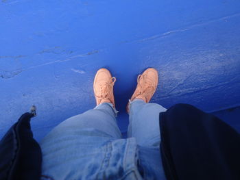 Low section of man standing against blue wall