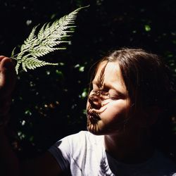 Close-up of girl with eyes closed holding leaf