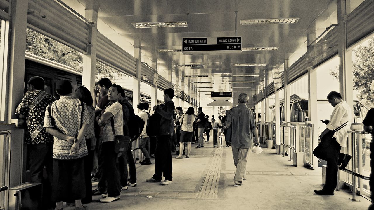 men, text, person, walking, large group of people, non-western script, western script, lifestyles, communication, architecture, built structure, transportation, the way forward, city life, city, store, shopping, leisure activity, sign