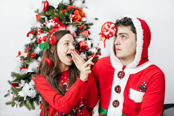 Smiling couple standing by christmas tree at home