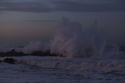 Scenic view of sea waves splashing on shore against sky