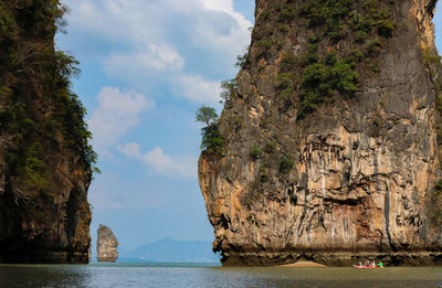 Rock formations in sea against cloudy sky