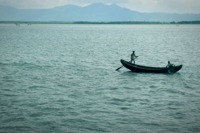 Man in boat on sea against mountain