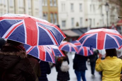 Rear view of people walking on road with umbrella