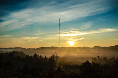 Silhouette trees on landscape against sky during sunset