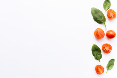 Flat lay with red cherry tomatoes, green spinach leaves on white background. healthy eating concept