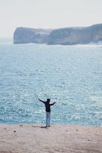 Rear view full length of man standing on shore at beach