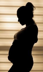 Side view of silhouette woman standing against window