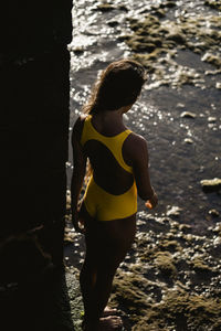 Portrait of beautiful latin woman in yellow swimsuit by the sea