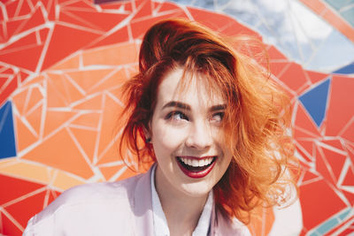 Smiling redhead young woman against mosaic wall