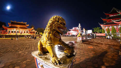 Statue of temple against building at night