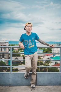 Portrait of young man standing against railing in city