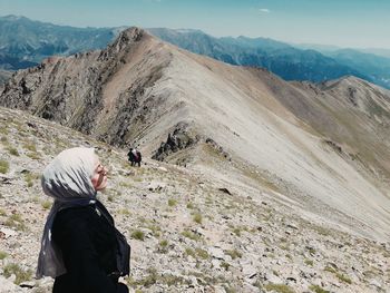 Side view of young woman looking at view against sky