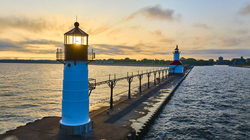 Lighthouse by sea against sky