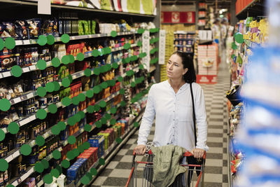 Thoughtful female customer buying groceries in supermarket