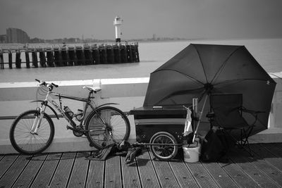 Bicycle with umbrella and chair on bridge against lighthouse