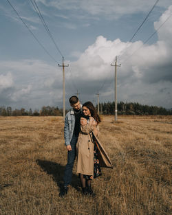 Couple standing on field against sky