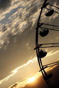 Low angle view of electricity pylon against cloudy sky