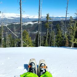 Low section of person wearing ski boots on snow covered landscape