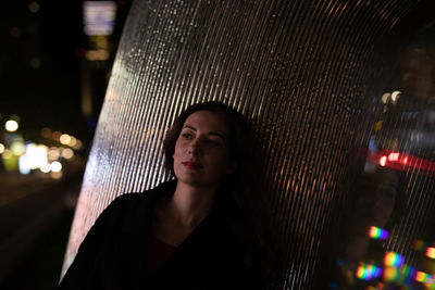 Mid adult woman leaning on pillar in city