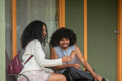 Young ethnic travelers with cellphone sitting on terrace in village of monte verde in costa rica