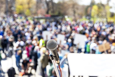 Protest or public demonstration, focus on microphone, blurred crowd of people in the background