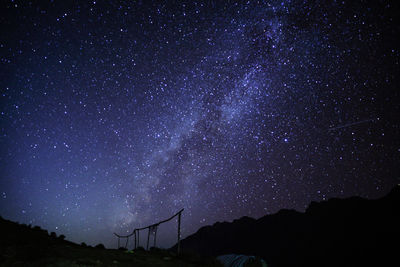 Low angle view of silhouette mountain against star field at night