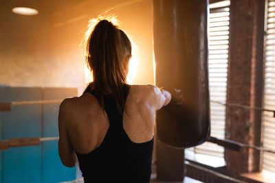 Rear view of woman standing against window