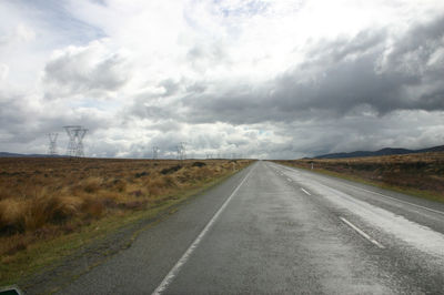 View of country road against cloudy sky