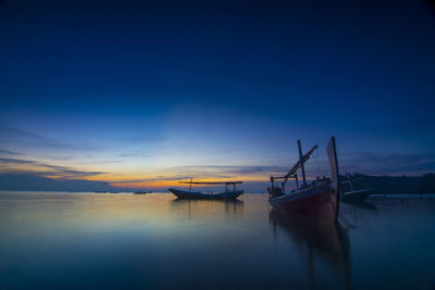 Boat moored in sea against sky during sunset