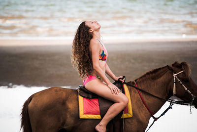 Woman riding horse at beach