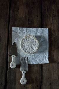 Camembert cheese with cheese fork and cheese knife on wooden rustic table