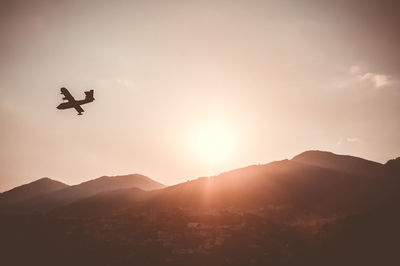 Low angle view of silhouette airplane flying against sky