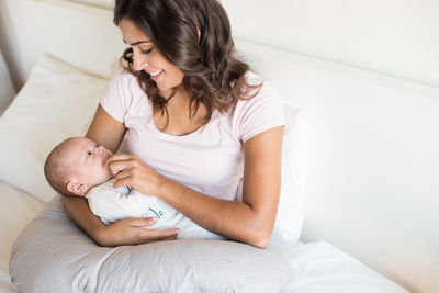 Smiling mother looking at son while sitting on sofa at home