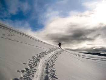 Person walking on snow covered land against sky