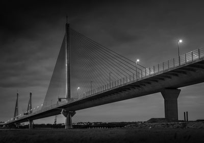 Low angle view of suspension bridge against cloudy sky