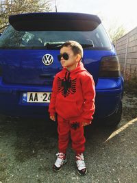 Full length of boy standing by car