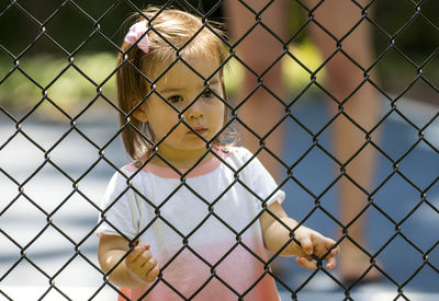 Portrait of boy seen through chainlink fence