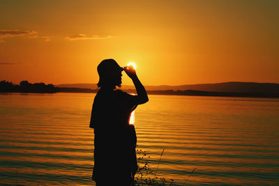 Silhouette man looking at sea against sky during sunset