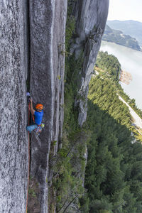 Side view of man climbing multi pitch route on pillar with ocean view