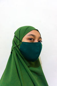 Portrait of young woman covering face over white background