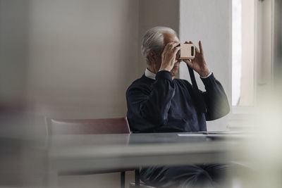 Senior man at home with cardboard vr glasses