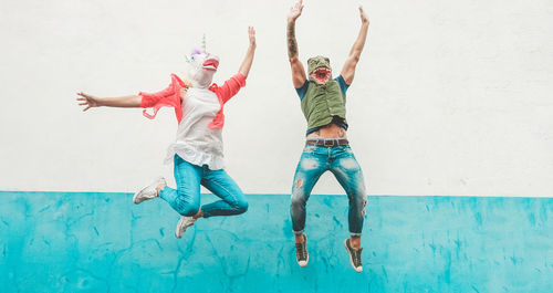 Low angle view of friends jumping against wall