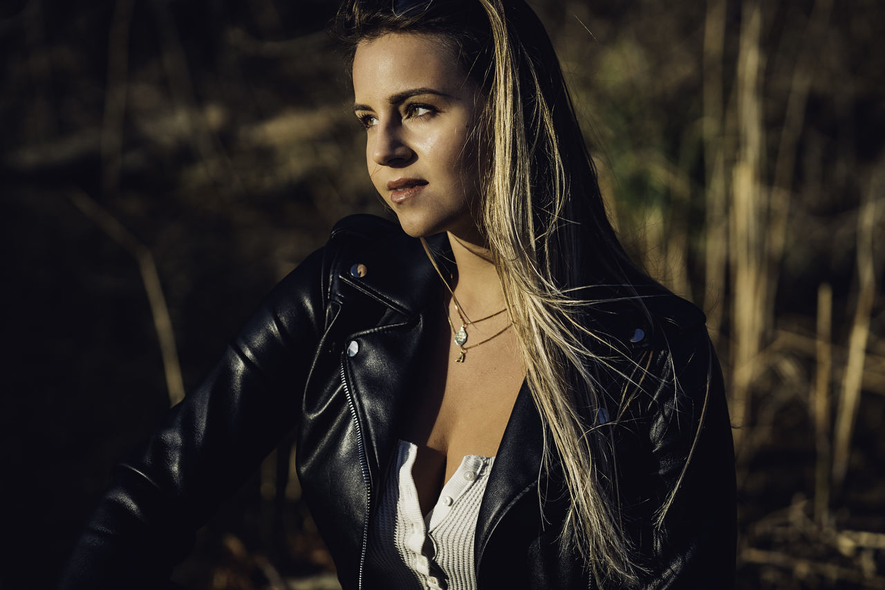 one person, young adult, young women, leather, jacket, beauty, beautiful woman, lifestyles, focus on foreground, real people, looking away, fashion, clothing, front view, leather jacket, leisure activity, hair, looking, portrait, hairstyle, outdoors, contemplation