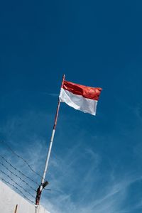 Low angle view of flag against blue sky